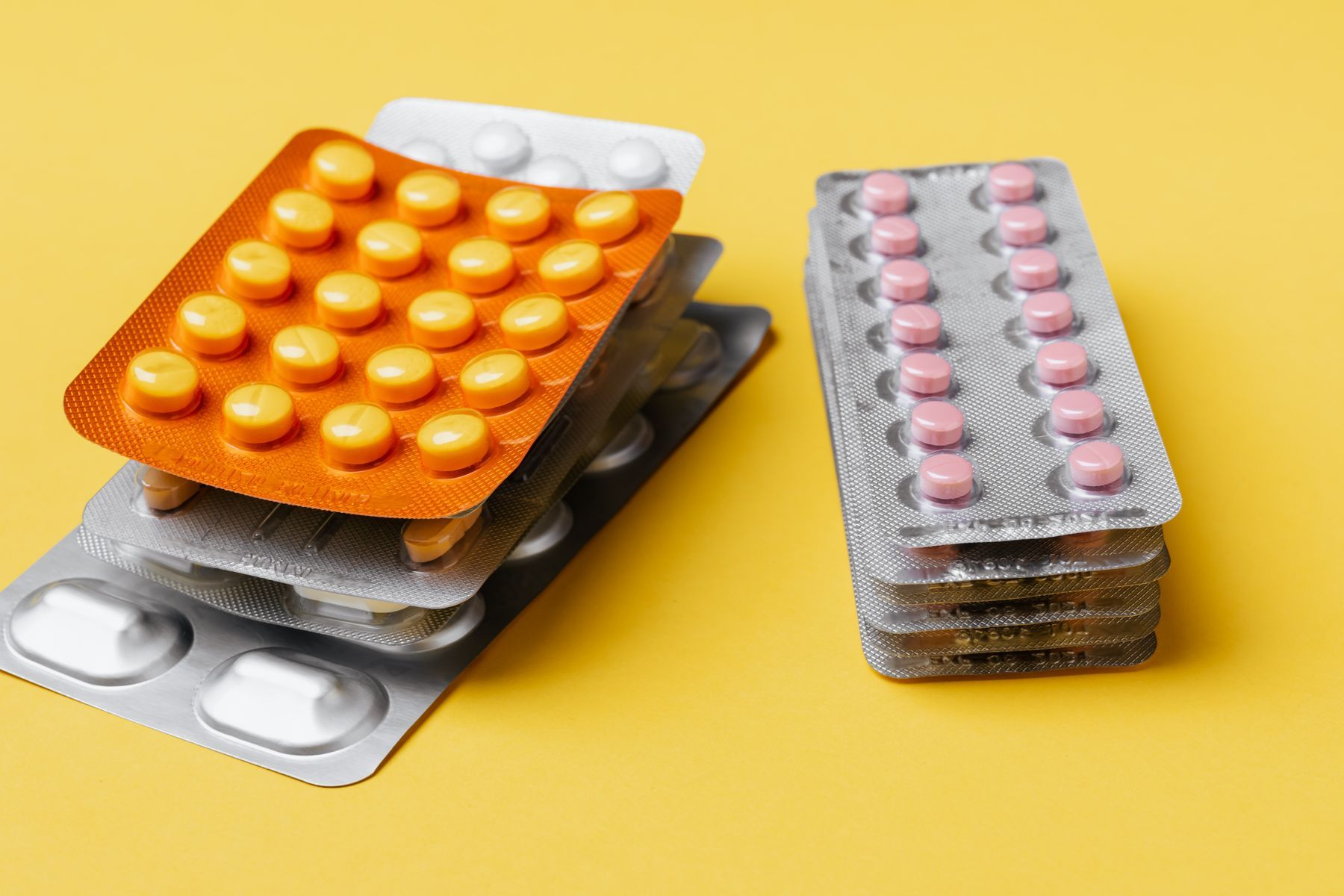 Stacked blister packs of tablets on a yellow background