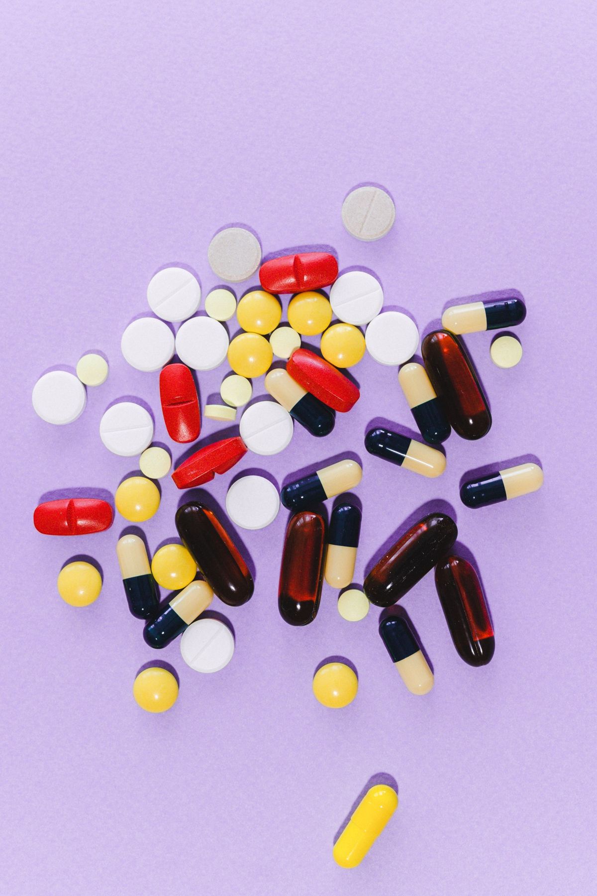 Assorted capsules and tablets on a lilac surface