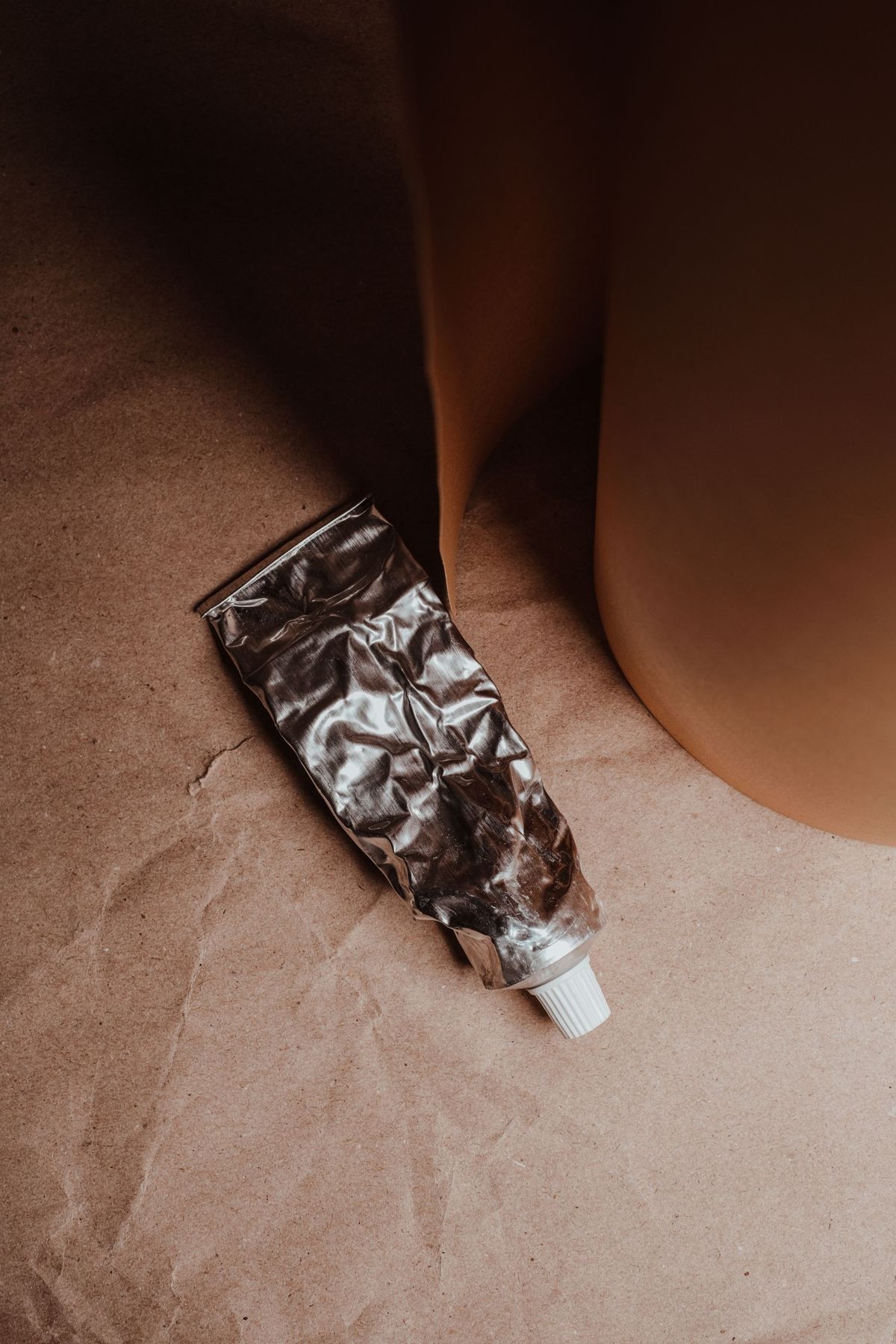 A silver ointment tube on brown paper